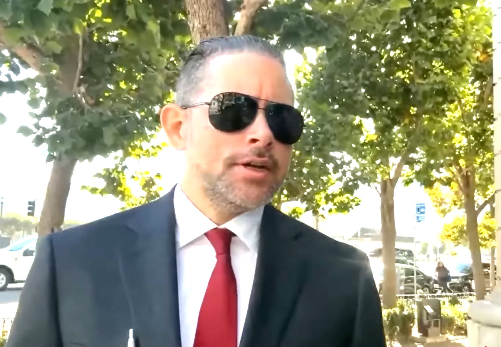 Omar Serrato outside the courthouse in a dark suit and red tie